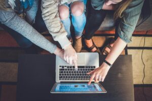 three female friends booking their vacation online through their laptop.