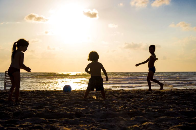 kids playing on a US Virgin Island beach as the sun sets.