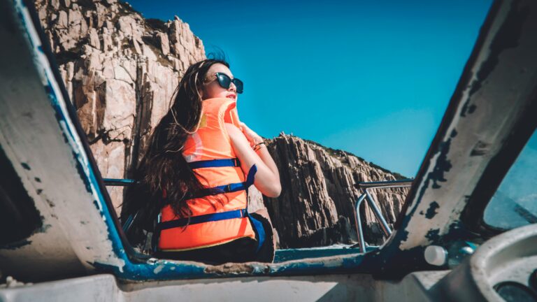 A woman sitting on the front of a boat, traveling between islands.