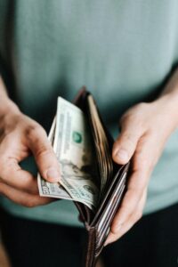 A man counting money in his brown leather wallet.