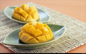 Peeled and sliced mango on a decorative plate that looks like a leaf.